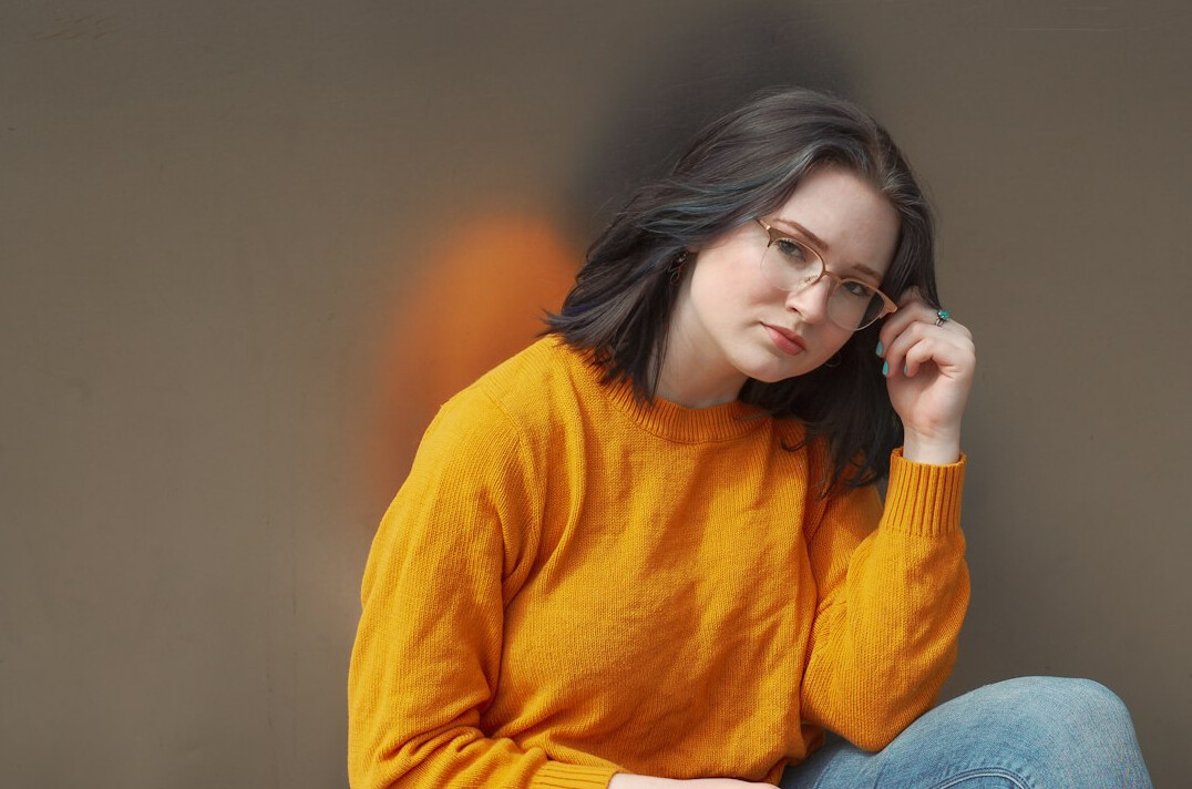 Portrait of a thoughtful adult with glasses against a plain background