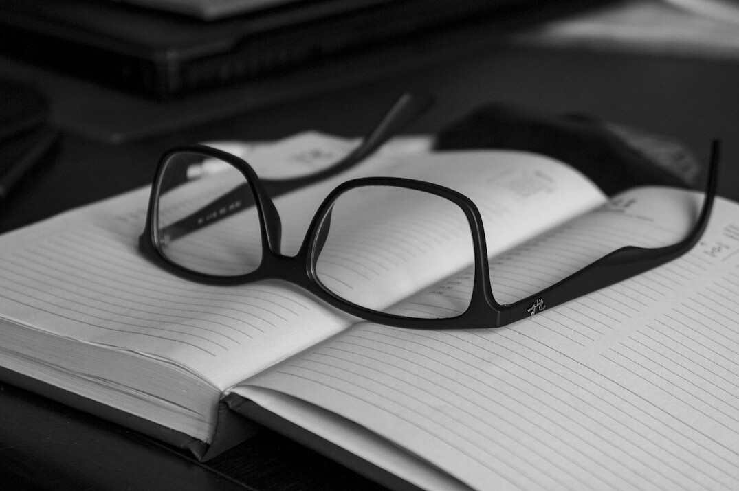 Open notebook with handwritten notes and a magnifying glass on a wooden desk
